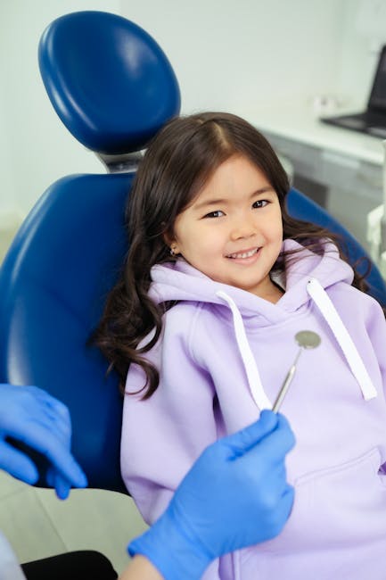 A young girl smiling while sitting in a dental chair, ready for her dental check-up.